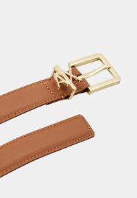 Cintura marrone con una fibbia dorata raffigurante le lettere "AX", che presenta dettagli cuciti e una texture in pelle liscia.