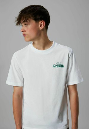 Witte katoenen t-shirt met een groene "Growth" graphic op de borst, korte mouwen, een ronde halslijn en een standaard pasvorm.