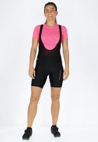 Svarta cykelbyxor med bärremmar, med en strukturerad rosa överdel. Noterbar logotyp från märket på byxorna, slätt tyg och figurnära design.
