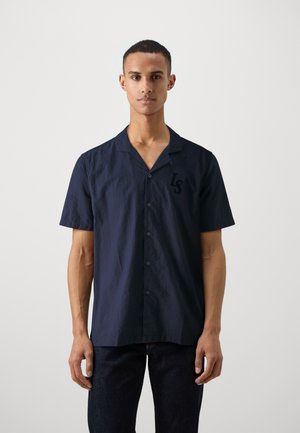 Chemise à manches courtes bleu marine à boutons, fabriquée dans un tissu texturé, avec un col décontracté et un logo sur la poitrine gauche de couleur assortie.