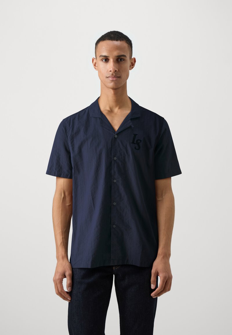 Camisa de botones de manga corta en color navy, hecha de tejido texturizado, con un cuello relajado y un logo en el lado izquierdo del pecho en un color a juego.
