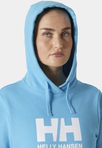 Jasnoniebieska hoodie z kieszenią z przodu, sznurkami i białym logo "HH". Miękka tkanina o gładkiej fakturze. Prosty design i luźny krój.