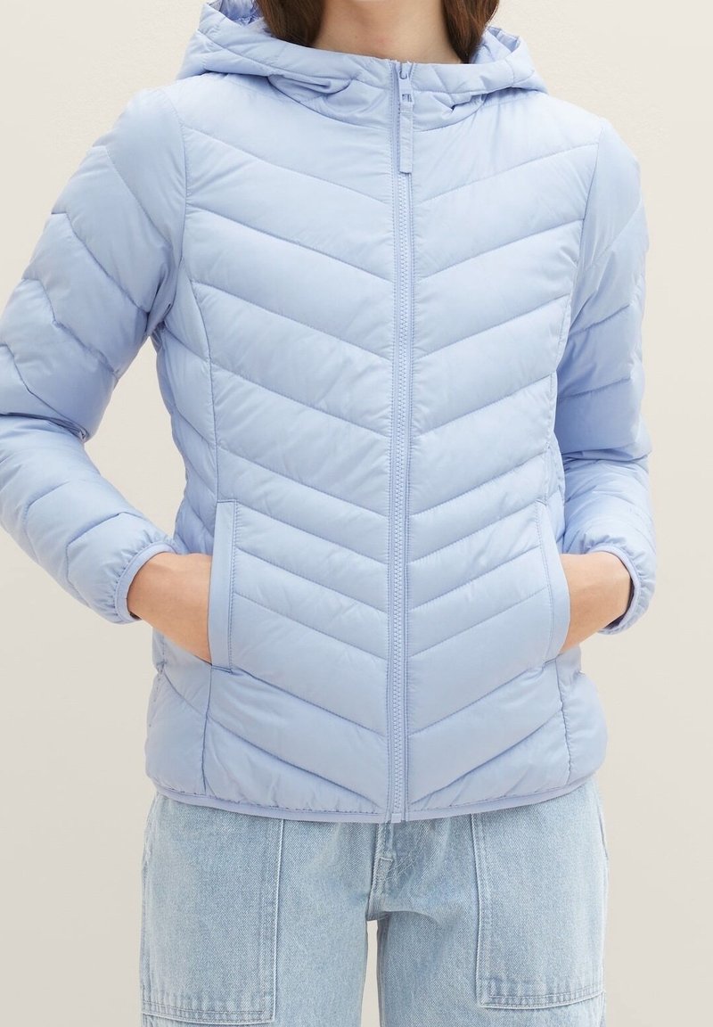 Světle modrá péřová bunda s kapucí, se zapínáním na zip, designem ve tvaru šípů a bočními kapsami. Hladká, lesklá textura.