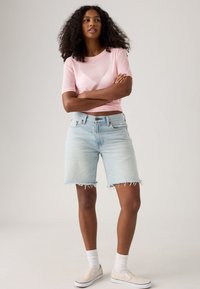 Shorts en denim bleu clair avec des ourlets effilochés, associés à un haut rose ajusté à manches courtes. Design simple et texture de tissu douce.