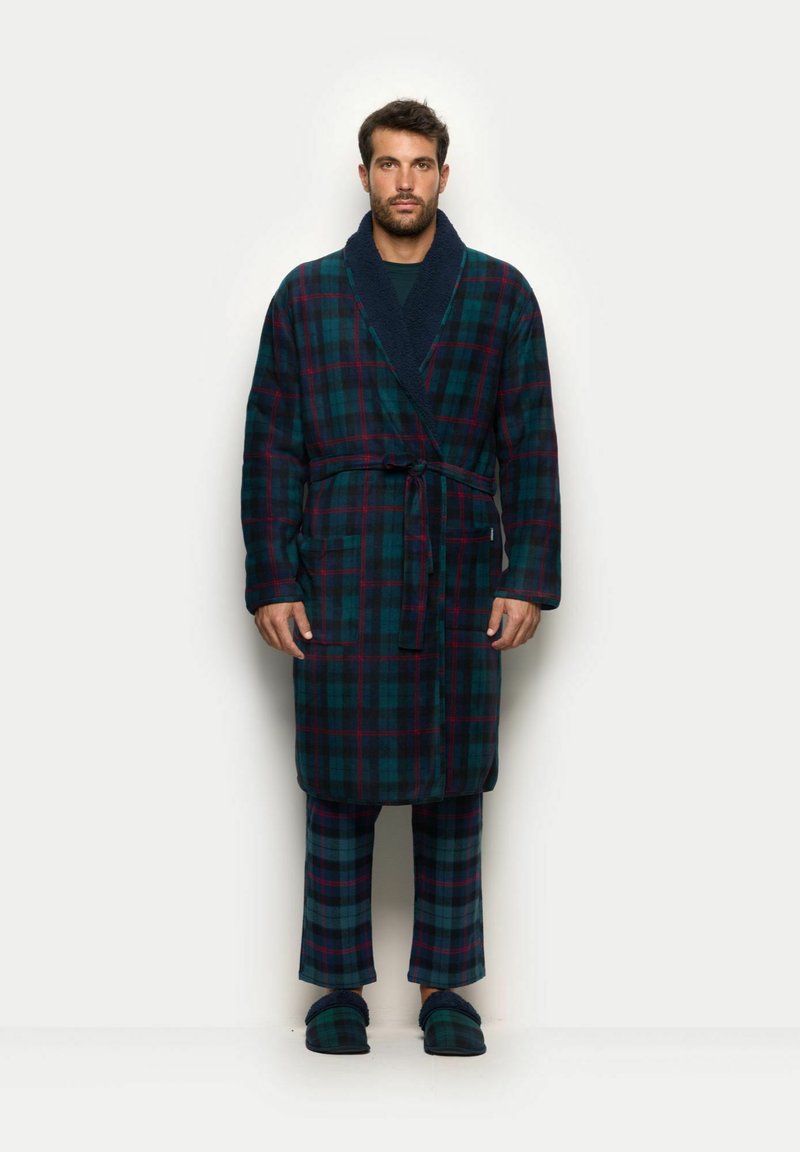 Rute badekåbe i mørkegrøn, blå og rød med sjalskrave, taljebånd og to sidelommer; parret med matchende rutede bukser og slippers.