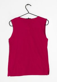 Haut sans manches magenta en tissu doux, avec un col rond et des fentes latérales, suspendu sur un cintre en métal noir contre un fond blanc.