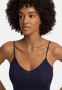 Námořnická modrá tílko s V-výstřihem, tenkými ramínky a žebrovanou strukturou. Lehce splývavá tkanina se těsně přizpůsobuje tělu.