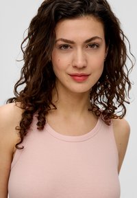 Hellrosa geripptes Tanktop mit Rundhalsausschnitt und schmalen Trägern, das eine glatte Textur und subtile Nähte aufweist.