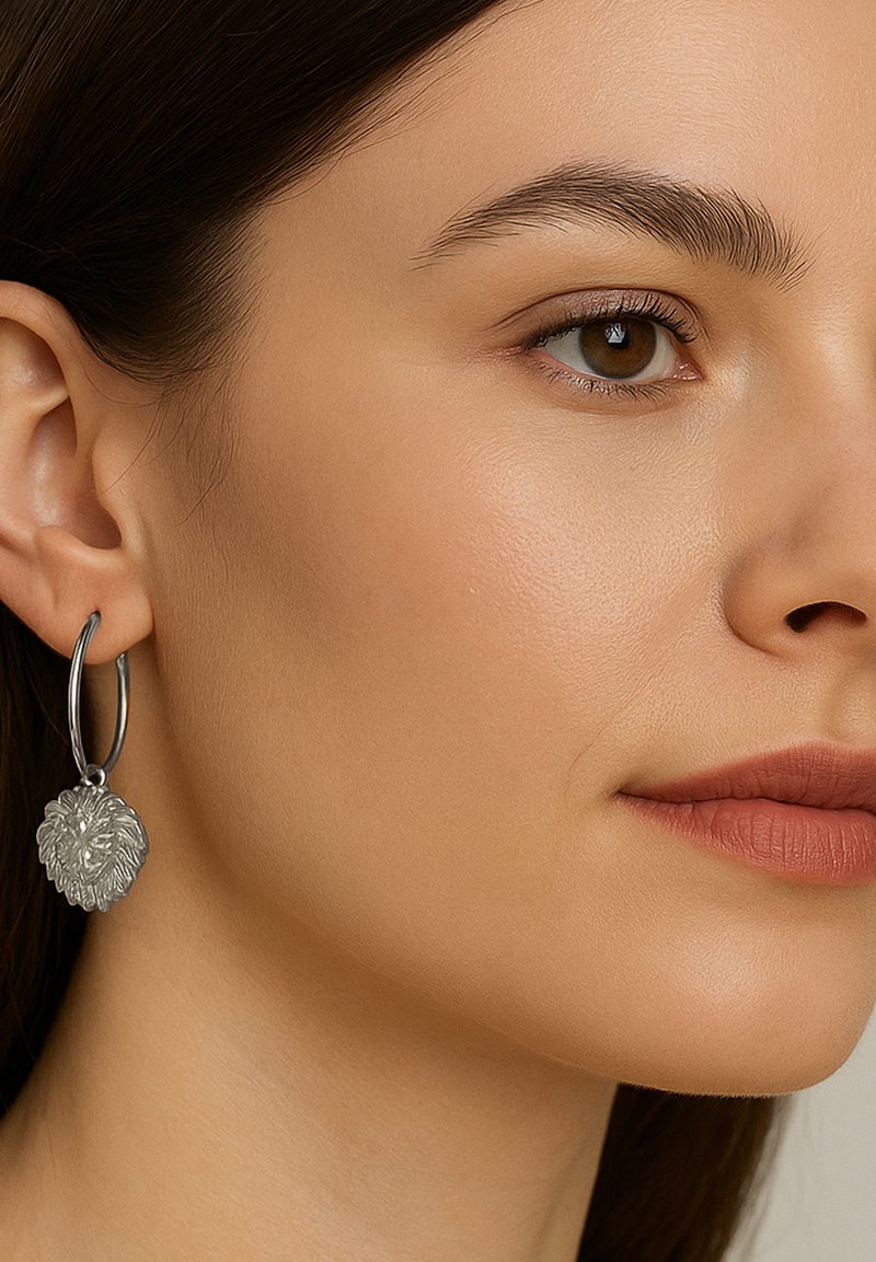 Silberne Creolen mit einem texturierten Löwenkopf-Anhänger, der detaillierte Fellmuster und eine polierte Oberfläche zeigt.