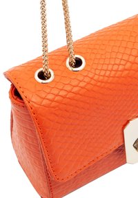 Sac à main en cuir orange avec un motif texturé en peau de serpent, doté d'une chaîne dorée et d'accents en métal sur le rabat avant.