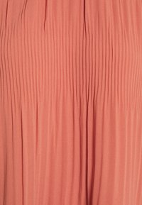 Tissu en corail clair plissé avec une texture verticale, surface lisse et drapé doux. Convient aux vêtements avec du volume et du mouvement.