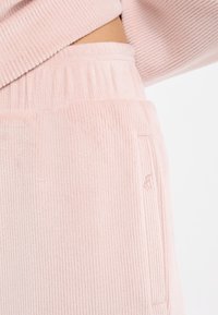 Pantalon de survêtement en velours côtelé rose avec une texture côtelée, doté d'une taille élastique et de détails subtils de poche.