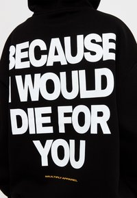 Sudadera negra con gran texto blanco que dice "PORQUE MORIRÍA POR TI." Pequeño logo amarillo "MULTIPLY APPAREL" cerca del dobladillo.