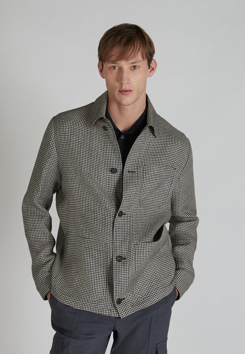 Kurtka w czarno-białą kratę, z kołnierzem, zapięciem na guziki i dwiema przednimi kieszeniami. Wykonana z fakturowanego materiału.