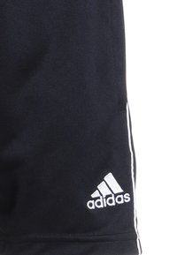 Mustat Adidas-urheilushortsit, joissa on valkoinen logo ja sivuraidat, näkyvät yksinkertaisella taustalla.