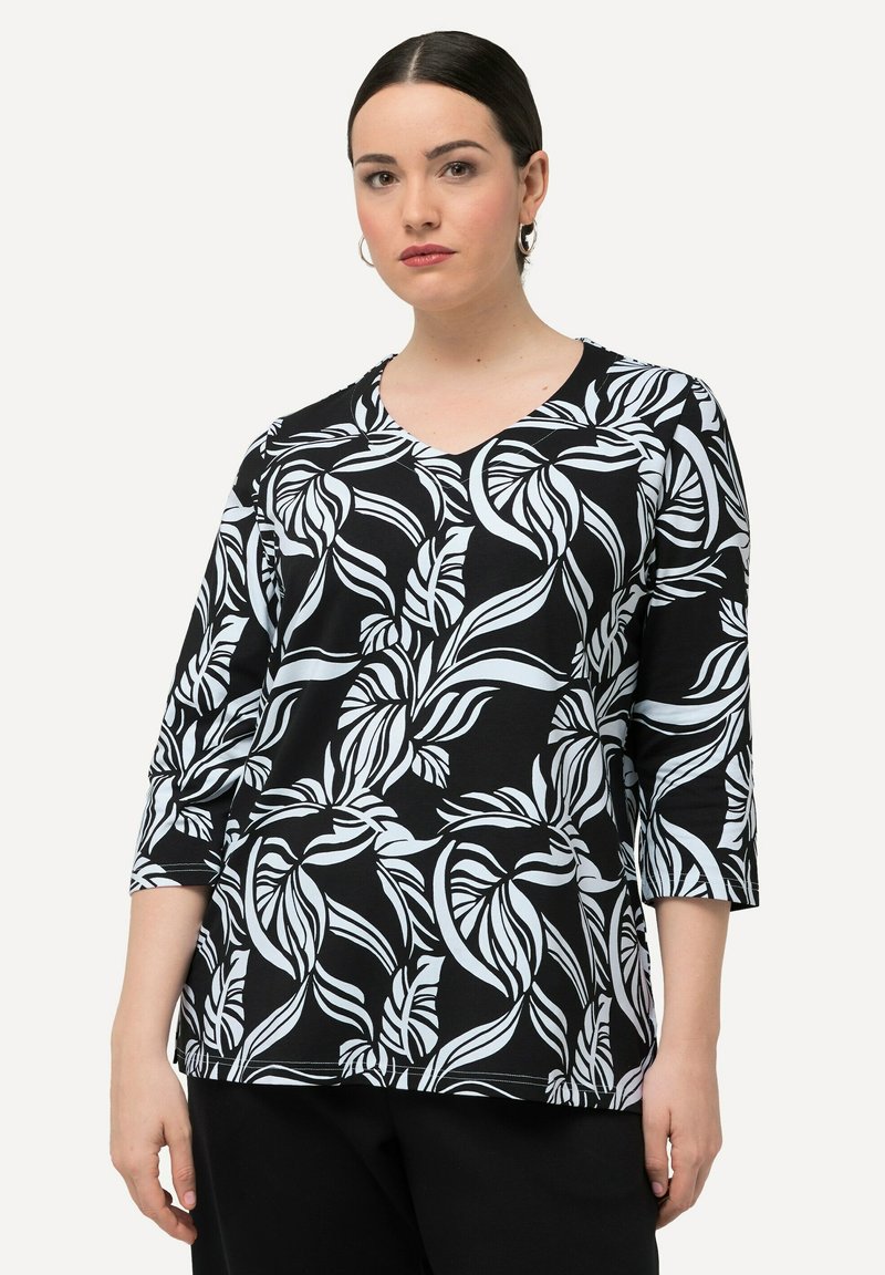 Černý top s bílým vzorem listů, výstřih do V a tříčtvrtečními rukávy. Vyrobeno z měkkého, elastického materiálu.