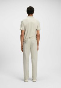Polo shirt beige chiaro con maniche corte, abbinato a pantaloni beige chiaro. Tessuto morbido e vestibilità su misura, con tasche posteriori.