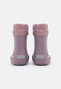 Botas waterproof moradas con un suave puño acolchado, textura lisa, material flexible y suela de goma plana. Acentos reflectantes en los laterales.