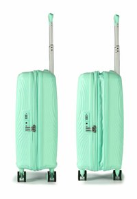 Valise à coque rigide vert menthe avec un motif ondulé texturé, poignée rétractable, serrure à combinaison et quatre roues noires pour la mobilité.