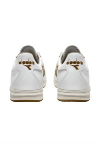 Sneaker bianchi in pelle con un design testurizzato, caratterizzati da un accento beige e un logo dorato sul tallone. Suola in gomma con una leggera scolpitura per una buona aderenza.