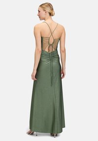 Metaliczna zielona wieczorowa suknia o dopasowanej sylwetce, z marszczeniami w talii oraz siateczkowym tyłem z akcentami w stylu sznurowania i cienkimi ramiączkami.
