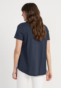  Marineblauw T-shirt met korte mouwen en een afgeronde zoom en zijsplitten, gemaakt van zachte katoenen stof. Van achteren weergegeven, met een ontspannen pasvorm.