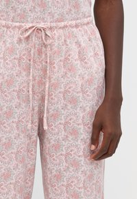 Rosa pyjamabyxor med ett paisleymönster, med resårmidja och dragsko. Tyget har en mjuk, bomullsliknande textur.
