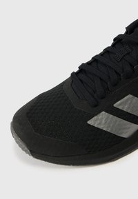 Czarne buty sportowe z teksturowaną siateczkową cholewką, płaskimi sznurowadłami i gumową podeszwą. Posiadają kontrastujące szare paski po bokach.