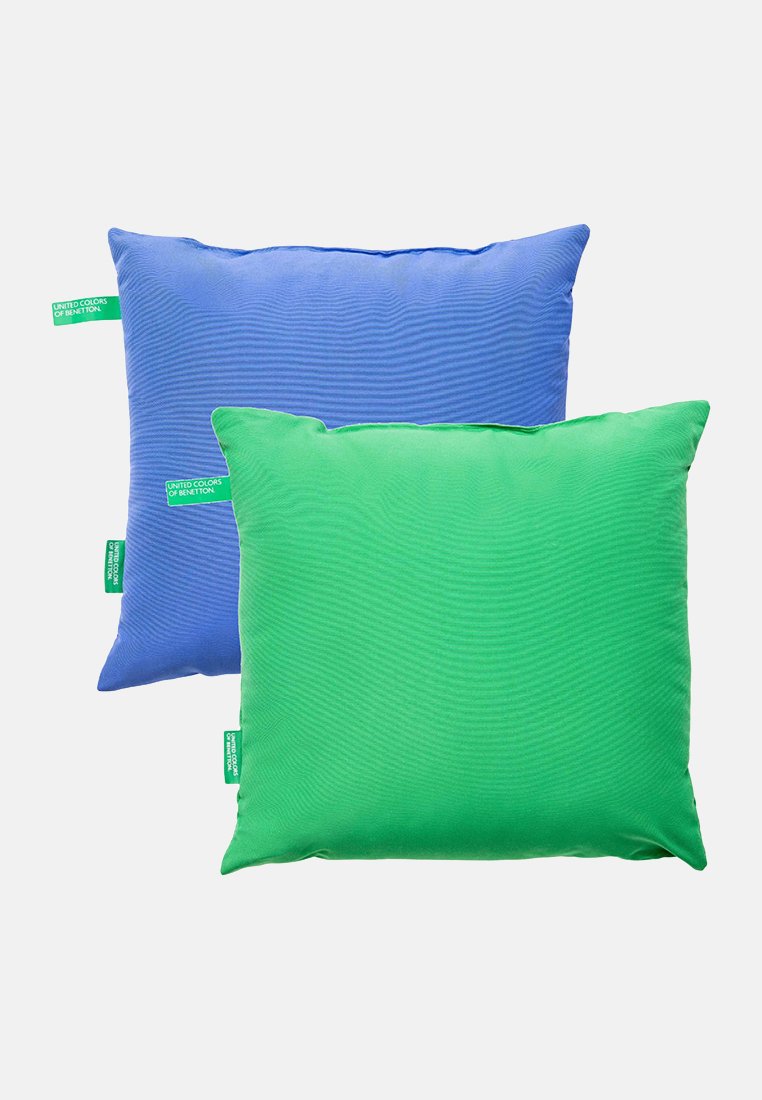 Niebieskie i zielone kwadratowe poduszki z metkami "United Colors of Benetton" na białym tle.