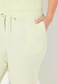 Limoengroene broek van lichtgewicht, textiel stof, met een elastische tailleband met trekkoord en zijzakken.