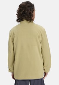 Lichtgroene fleece jas met een hoge kraag, lange mouwen en een relaxte pasvorm. Zachte textuur, zonder zichtbare patronen of hardware.