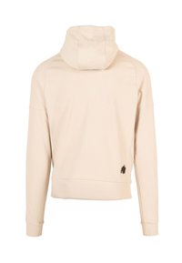 Beige hoodie met een gestructureerde afwerking. Heeft lange mouwen en een klein zwart logo op de linker onderrug.