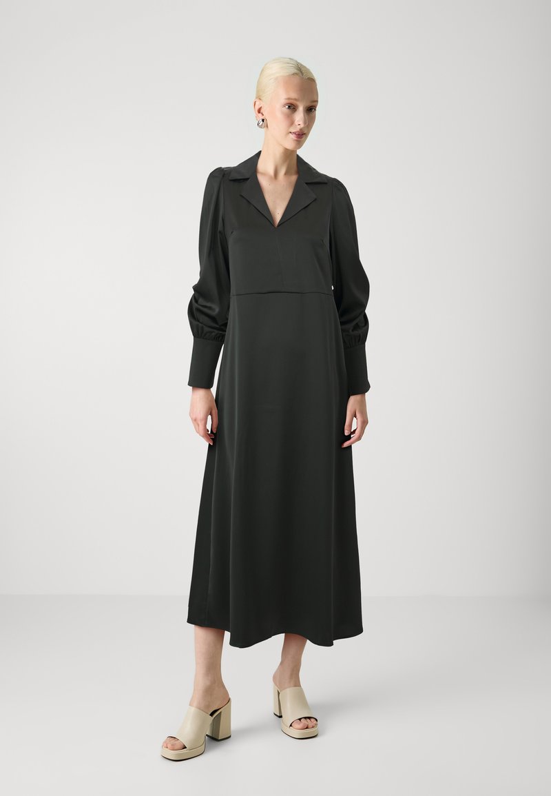 Black maxi dress with a collar, puffed sleeves, and a fitted bodice. Smooth fabric texture. Paired with beige block-heeled mules.
