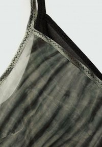 Débardeur gris translucide avec des bretelles foncées, présentant une texture lisse et un léger motif ondulé. Coutures piquées le long des bords.