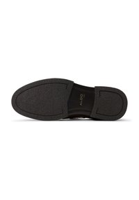 Scarpa nera slip-on con suola in gomma testurizzata, punta arrotondata e tomaia in pelle liscia. Branding visibile all'interno dell'area del tallone.