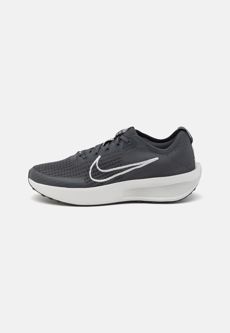 Scarpe da corsa Nike di colore grigio scuro con una parte superiore testurizzata, logo swoosh bianco e suola bianca imbottita. Presentano un design con lacci.