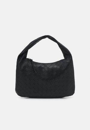 Sac à main en cuir tressé noir avec une poignée unique et une fermeture éclair sur le dessus, sur un fond clair uni.