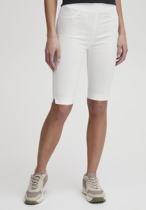 Weiße Denim-Bermuda-Shorts mit schlanker Passform, ausgestattet mit Fronttaschen und umgeschlagenen Säumen, kombiniert mit hellgrauen Sneakers.