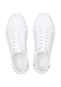 Białe sneakersy z perforowanymi bokami, płaskimi sznurówkami, zaokrąglonymi noskami, teksturowanym wierzchem i srebrnymi metalowymi akcentami na pięcie. Płaskie gumowe podeszwy.