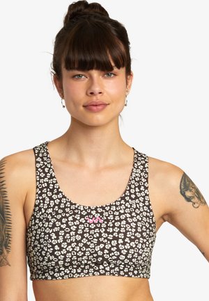 Bralette marron à motifs avec des designs floraux blancs, décolleté en scoop, bretelles épaisses et un petit logo rose à l'avant. Texture de tissu douce.