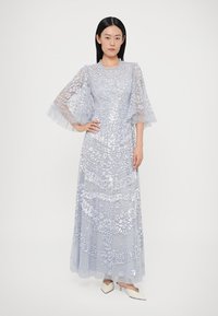 Helehall sinine maxi-kleit lillelisi tikandeid, kihilisi tüllvarrukaid ja vormitud ülakehaga, mis suubub voolavasse seelikusse. Kaunistatud litritega.