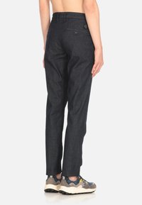 Pantaloni in denim scuro con una vestibilità slim, dotati di tasche posteriori e dettagli di cucitura discreti. Indossati con sneakers, mostrano un design a gamba dritta.