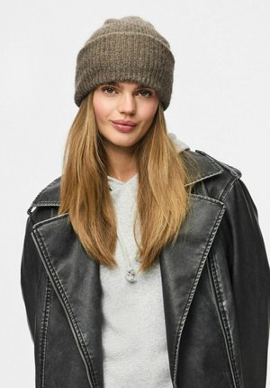 Brązowa dzianinowa czapka beanie o prążkowanej fakturze, noszona z szarym hoodie i czarną skórzaną kurtką z dużymi klapami i zamkiem błyskawicznym.