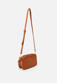 Bruine leren crossbodytas met geweven ontwerp bovenop, effen body, verstelbare riem en accenten van goudkleurig beslag.