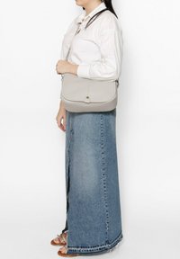 Lichtgrijze leren schoudertas met klepsluiting, voorzien van een voorste stiksel detail en een afneembare schouderband. Gladde textuur en minimalistisch ontwerp.