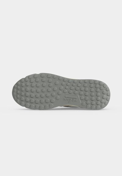 Semelle de chaussure avec des clous en caoutchouc ronds pour l'adhérence, présentant un logo en relief au centre sur un fond uni.