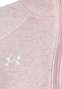 En rosa fleecejacka med texturerad tyg, full dragkedja och en broderad vit logotyp på vänster bröstområde.