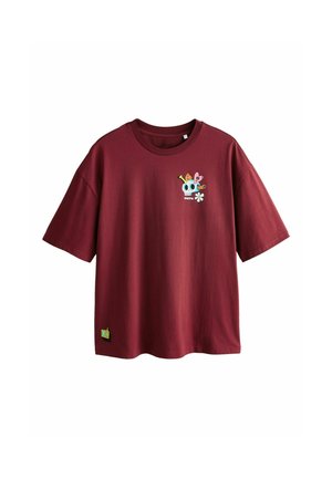 Dunkelrotes T-Shirt mit kurzen Ärmeln und Rundhalsausschnitt, das auf der Brust eine kleine bunte Grafik mit Totenkopf und Blumen zeigt und nahe dem Saum einen gelben "ok"-Aufnäher trägt.