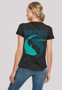 Black cotton t-shirt featuring turquoise koi fish design on the back, with bold text and a curved pattern highlighting the artwork.