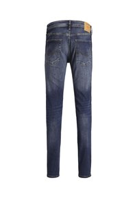 Jeans slim fit blu scuro mostrati da dietro con due tasche posteriori e un patch in pelle color cuoio sulla vita.